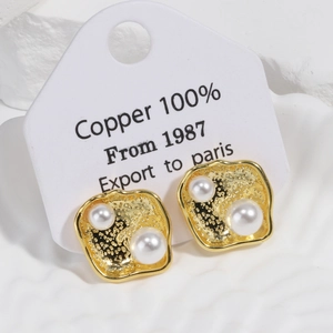 Detail of 18k gold plated square lava earrings featuring white pearls and textured finish