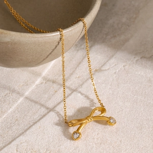 Close-up of 18k gold plated bow pendant with sparkling white zircons on stone surface