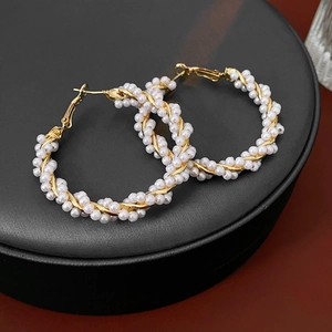Detailed view of pearl-wrapped gold large hoop earrings on a premium black leather tray