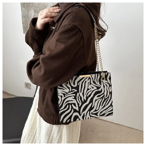 Detail of zebra pattern shoulder bag with gold chain strap worn by a fashion model