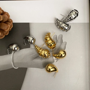 Macro shot of gold and silver teardrop earrings with spiral texture on magazine