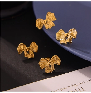 Detail der eleganten goldenen Ohrstecker in Schleifenform auf stilvollem Hintergrund