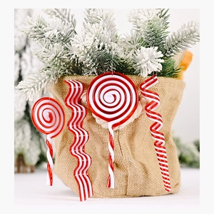 Close-up of red and white candy cane ornaments hanging on festive green pine branches