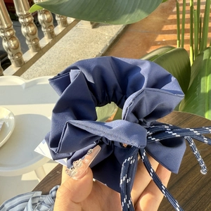 Close-up of navy blue fabric hair scrunchie with blue and white drawstring bow detail
