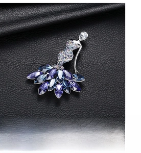 Detailed macro view of an elegant ballerina brooch with blue and purple crystals on black leather