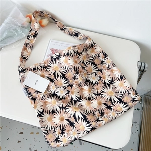 Detail of floral canvas tote bag with daisy pattern and MISS brand tag on white desk