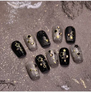 Detail of dark starry night press-on nails with gold star patterns and rhinestones