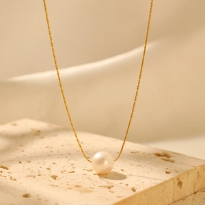 Elegant gold stainless steel necklace featuring a single round pearl on a stone pedestal
