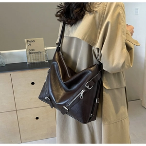 Detail of a large dark brown faux leather hobo bag with multiple silver metal zippers