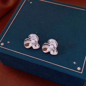 Detailed view of silver flower earrings with pearls on a blue gift box background