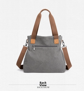 Detail of grey canvas bag back showing zip pocket and brown leather reinforcements