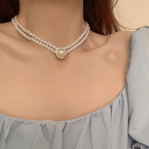 Détail d'un collier de perles baroques double épaisseur avec pendentif strass sur le cou