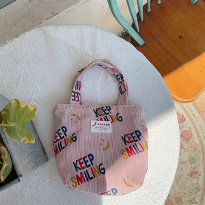 Petit sac en velours côtelé rose avec imprimé Keep Smiling sur une nappe en dentelle