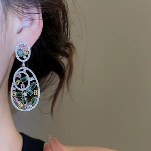 Detailed close-up of model wearing luxury multi-color gemstone drop earrings with zircons