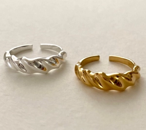 Detailed view of adjustable silver and gold croissant twist rings in a minimal style