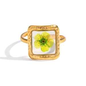 Detail of golden ring with hammered texture and yellow dried flower in square resin