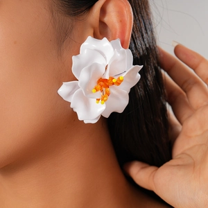 Detailed view of oversized white acrylic flower earrings with orange beaded centers