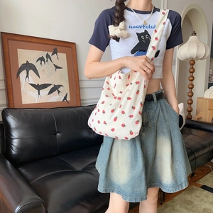 Gros plan sur le sac en velours côtelé crème avec un motif fraises rouges imprimé