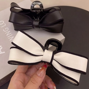 Detail view of large French bow hair claws in black and white faux leather finish