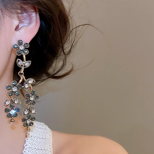 Close-up of dangling rhinestone flower tassel earrings with blue and clear crystals