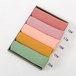 Detail view of colorful bamboo cotton scarves in a wooden tray with tassel edges