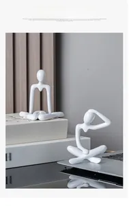 Detail of white resin abstract human sculptures in a cozy modern home office setting