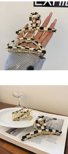 Detailed close-up of geometric black and white checkered hair clips with gold metal base