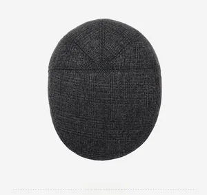 Top view of dark grey flat cap showing thick wool-like woven texture and top button
