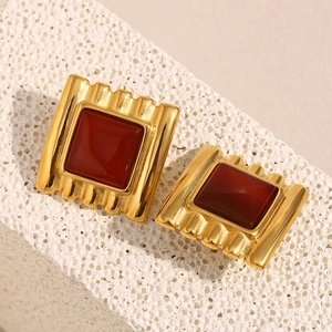 Macro detail of 18K gold-plated square stud earrings featuring a red stone inlay
