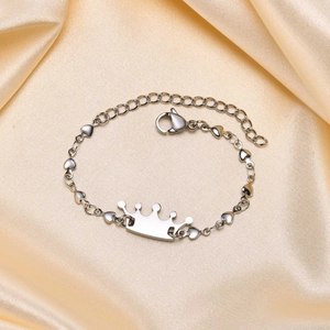 Macro shot of silver crown bracelet with heart links on champagne satin fabric