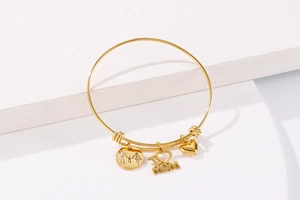 Detail of adjustable gold bangle featuring family silhouettes and I love MOM charms