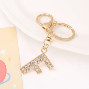 Macro view of gold letter F keychain with crystal rhinestones on white tray
