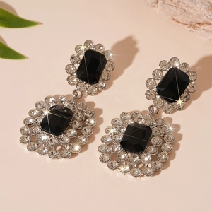 Detailed view of silver drop earrings with black rectangular stones and crystals