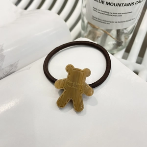 Close-up of a brown resin bear pendant engraved with Amy Bear on a brown hair tie