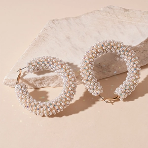 Detailed view of gold hoop earrings with pavé set pearls and sparkling crystals