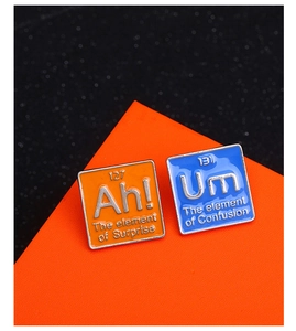 Gros plan sur les pin's tableau périodique Ah! et Um sur un présentoir orange