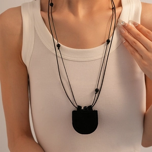 Detail of a minimalist black faux leather heart-shaped storage necklace on a model
