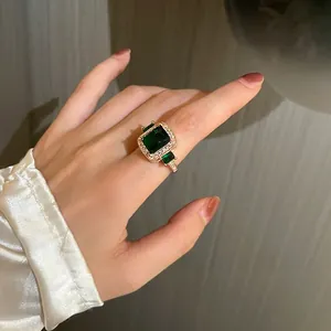 Detail of emerald cut green gemstone ring with white crystals on a gold band