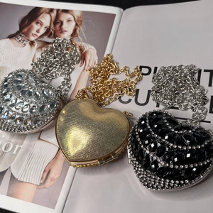 Three heart-shaped evening bags in gold, silver and black with elegant metal chains