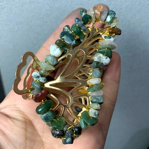 Macro shot of butterfly hair claw with natural green stones and golden metal frame