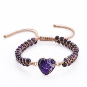 Detail of a purple heart-shaped stone on a khaki braided bracelet with purple beads