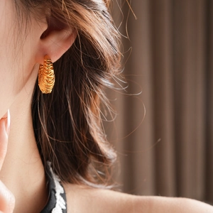 Detailed view of 18k gold plated hoop earrings featuring a woven textured design on model