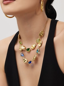 Detail of layered gold necklace with teardrop gemstones and matching round earrings