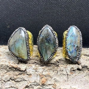 Detail of three wide golden hammered rings with irregular blue labradorite stones