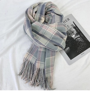 Detail of plaid scarf with soft fringe and pastel check pattern on white fabric