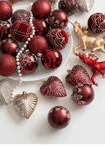 Flat lay of red and gold Christmas ornaments including glitter baubles and reindeer