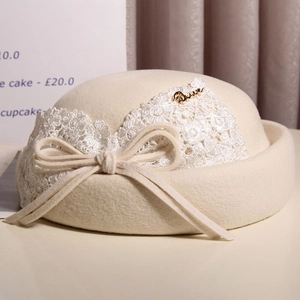 Detail of elegant wool beret with lace floral embroidery and gold Queen plaque