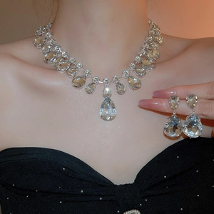 Macro shot of sparkling waterdrop crystal pendant necklace and earrings set on silver base