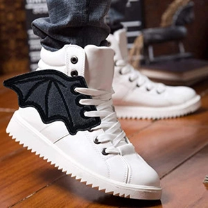 Detail of white high-top platform sneaker with black bat wing charm accessories