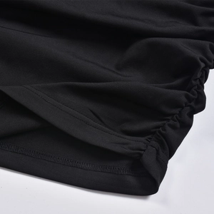 Dettaglio di un abito in maglia nera con coulisse laterale e tessuto testurizzato